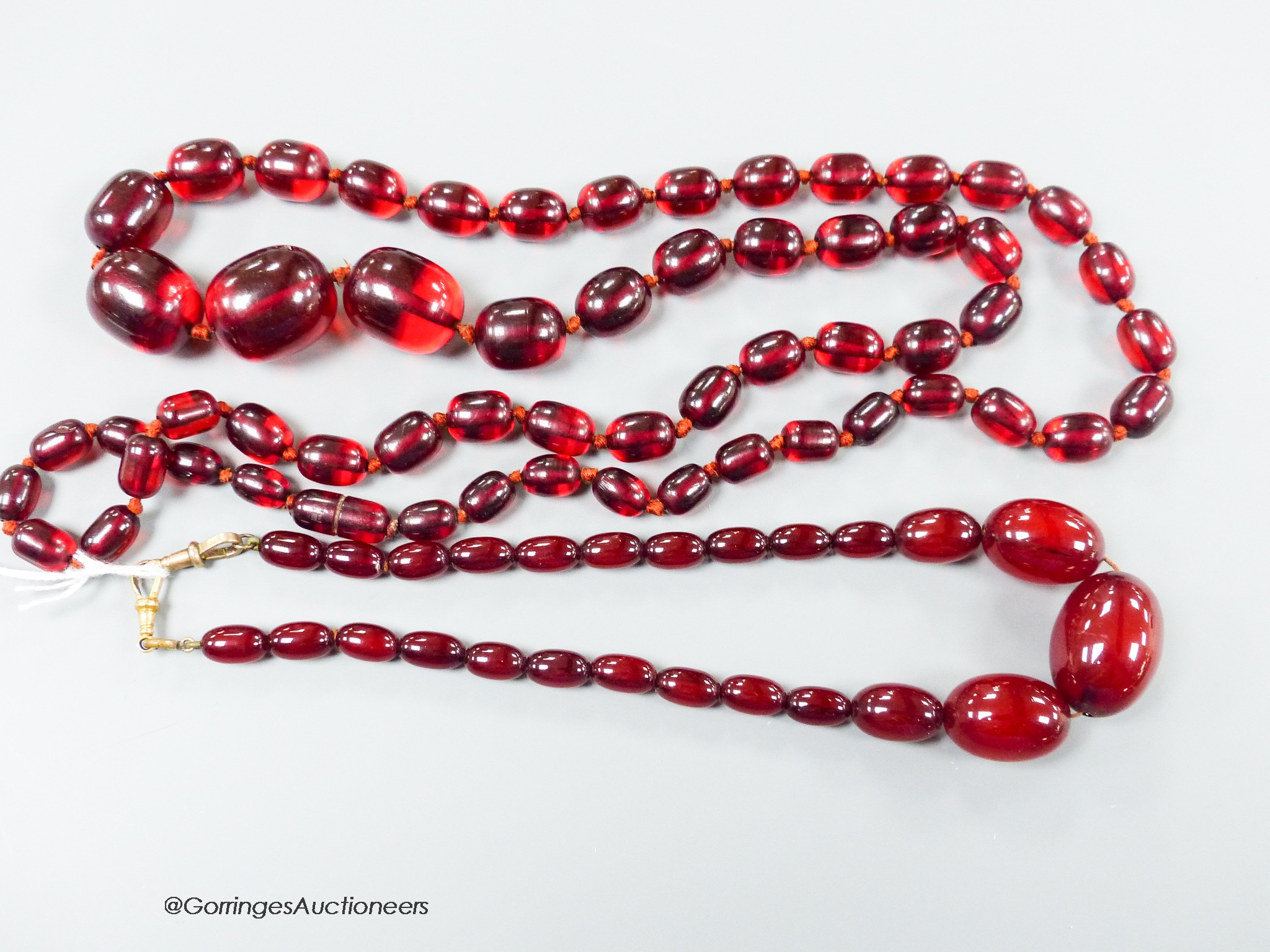 Two single strand graduated simulated cherry amber oval bead necklaces, longest 98cm, gross weight 134 grams.